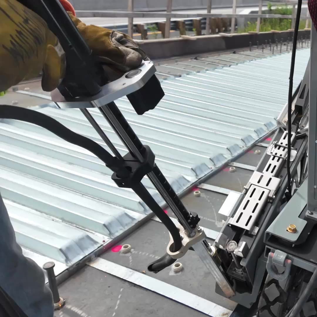 Gloved hands guiding the welding gun as Stud Caddy feeds a stud into place