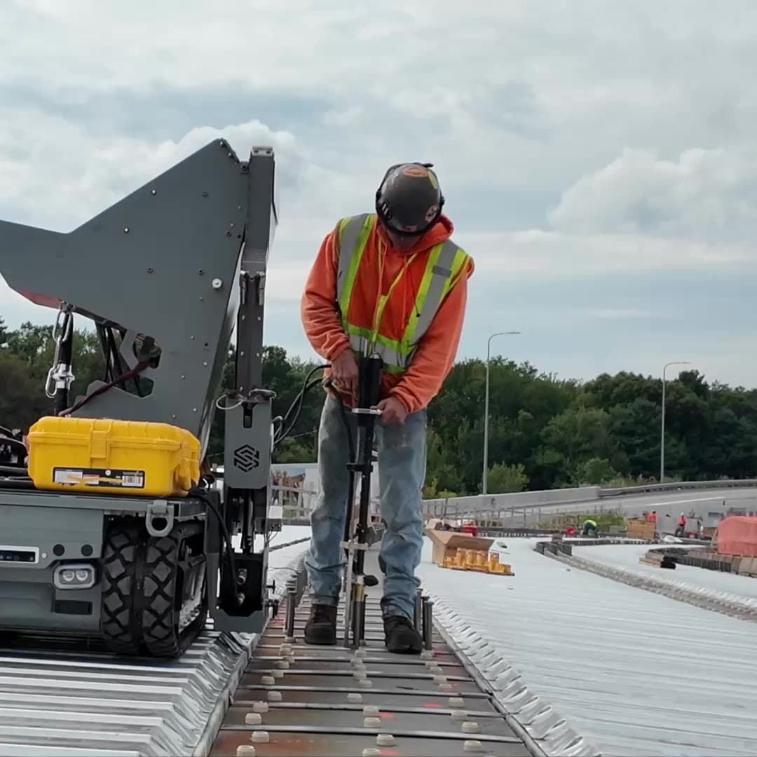 Operator welding a stud while standing upright beside Stud Caddy