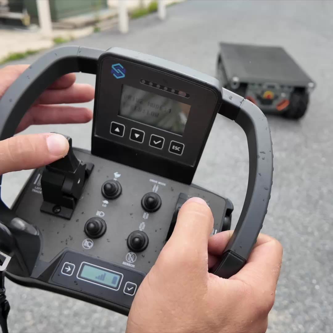 Hands on the wireless remote with Site Runner driving in the background